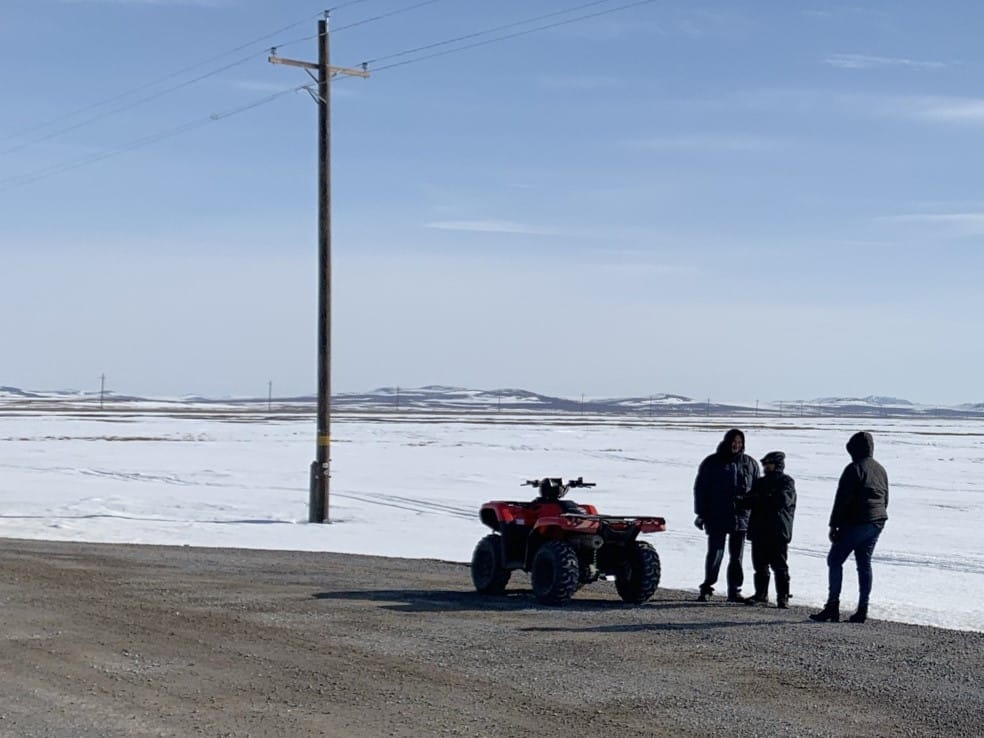 people with a fourwheeler in front of a snowy landscape